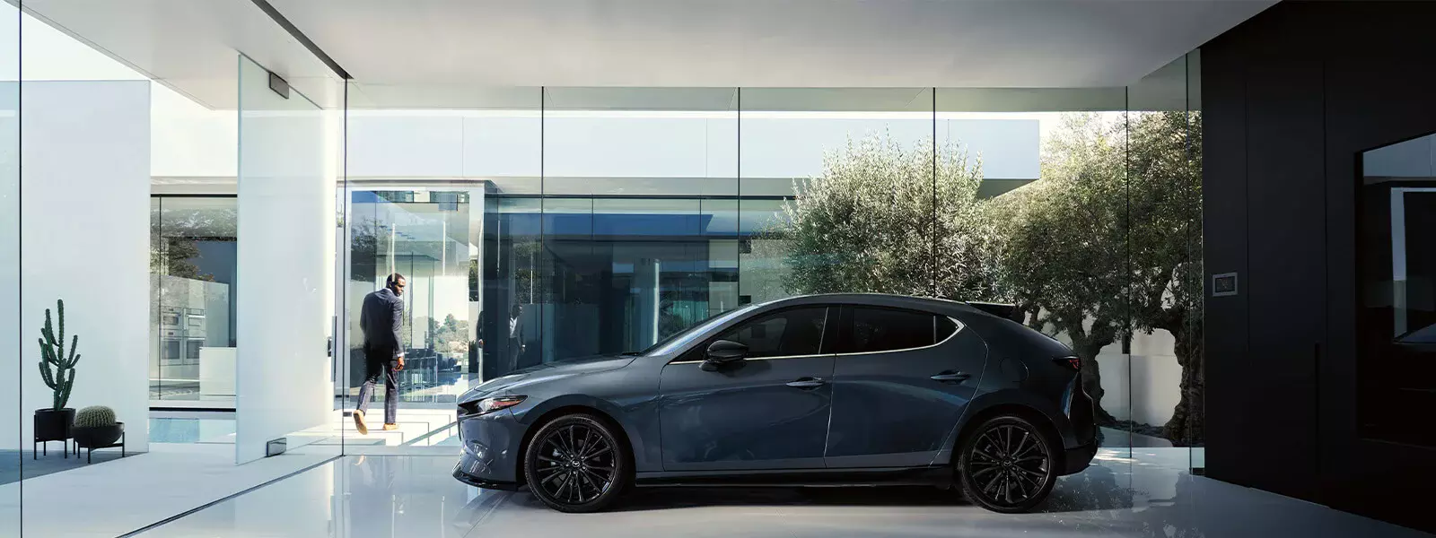 Customer leaving a Mazda showroom with a blue Mazda3 Sport on display